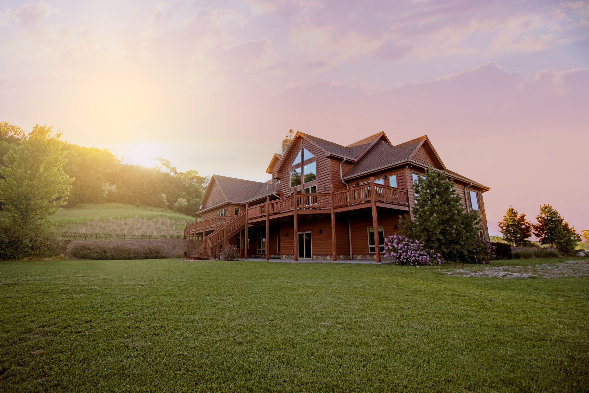 Log Home with Large Lawn, Trees in the Background, and a Sunset