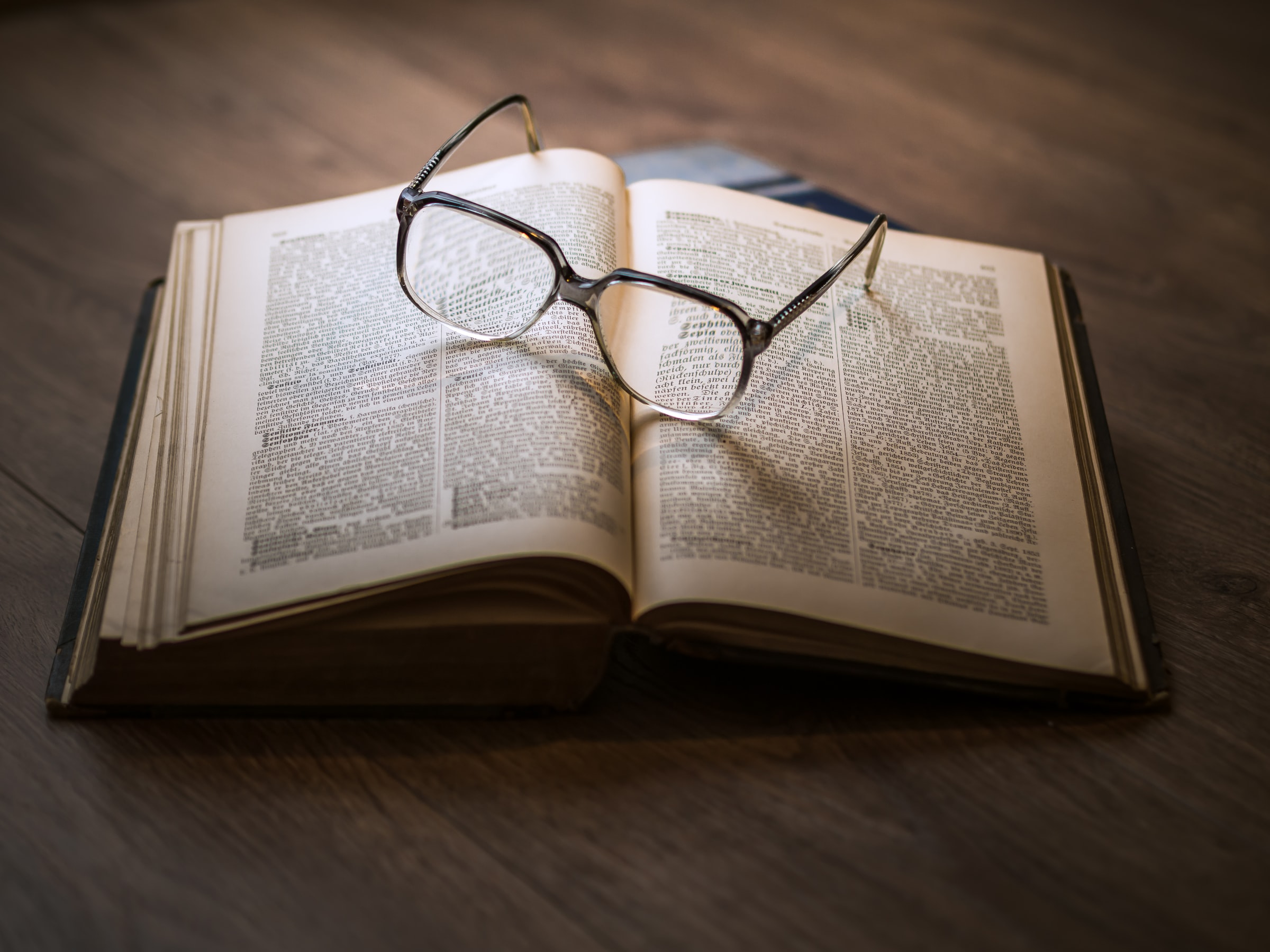 Pair of Glasses Sitting on top of an Open Book