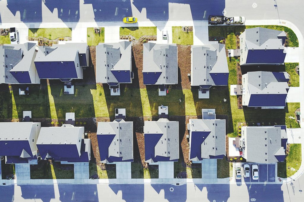 Aerial shot of neighborhood with white and grey houses and lawns