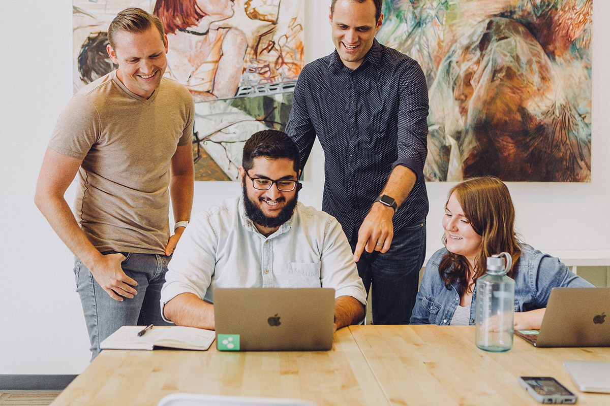 Team of office workers looking at a laptop