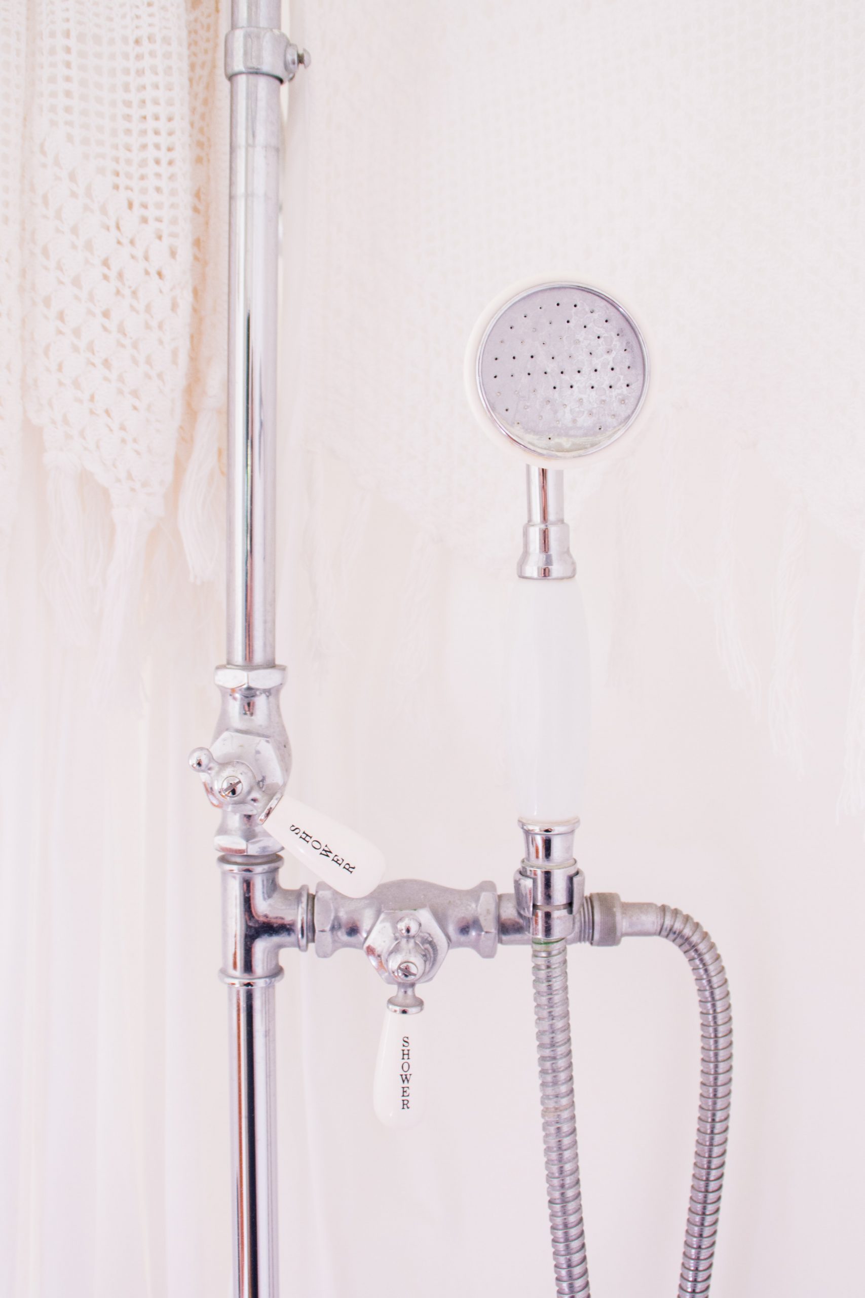Exposed chrome plumbing pipes in shower with detachable showerheat
