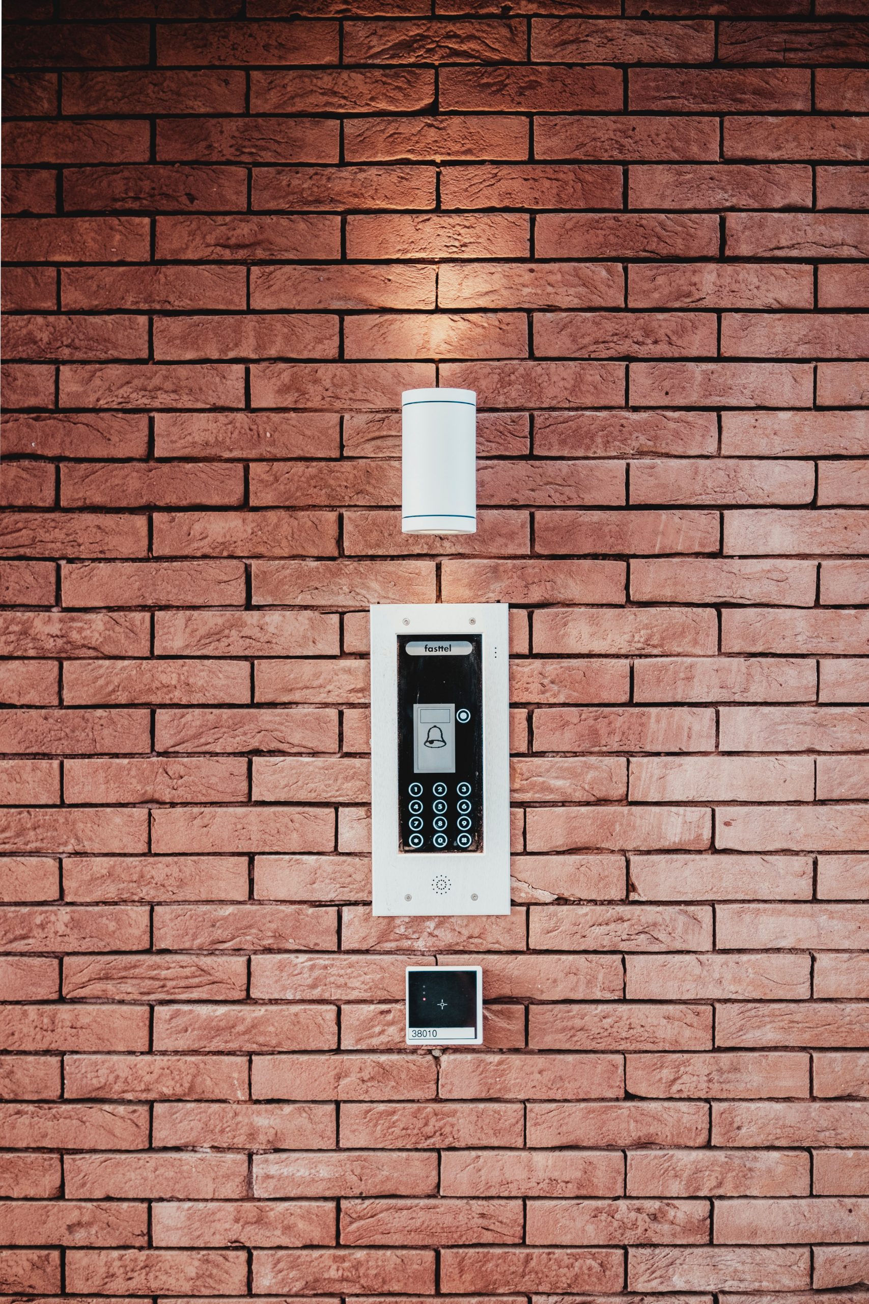 Brick wall with light and security alarm panel below it