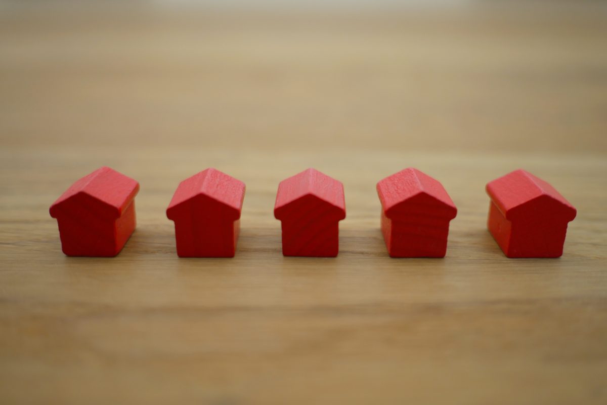 Row of tiny red wooden houses on a wood surface