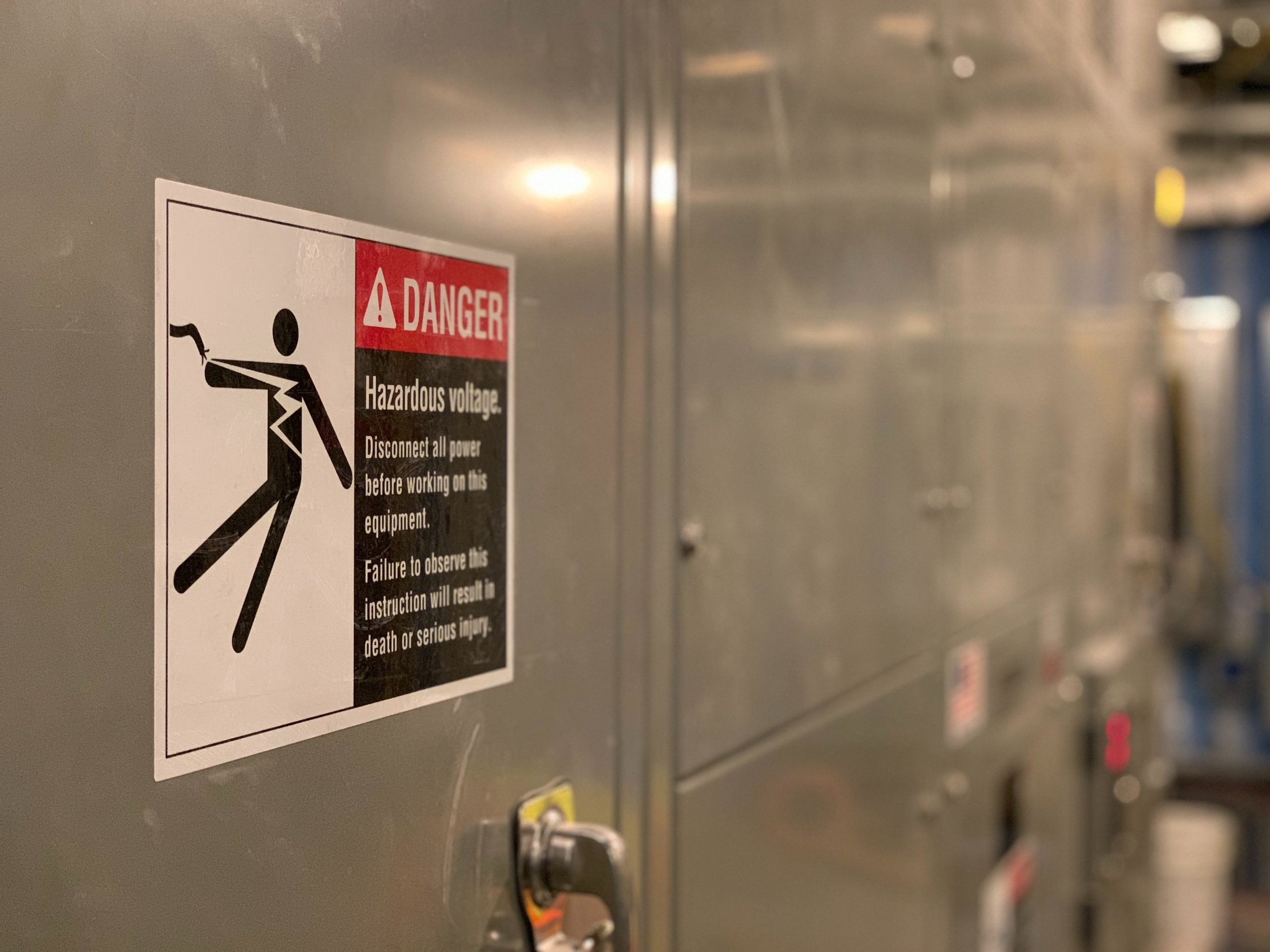 Danger sign warning of hazardous voltage on grey metal door
