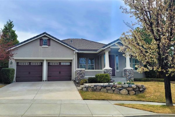 Grey house with purple garage doors and front door, and a cherry blossom tree in front yard